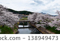 A bridge spanning the river and rows of cherry trees on both banks, overlooking the townscape. 138949473