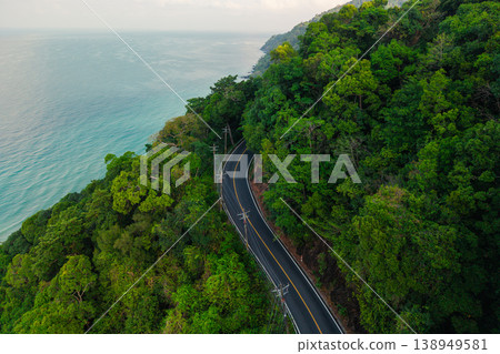 Aerial top-down view of a winding asphalt road cutting through lush green tropical jungle and beautiful coastline. Aerial top-down view of a winding asphalt road cutting through lush green tropical jungle and beautiful coastline. 138949581