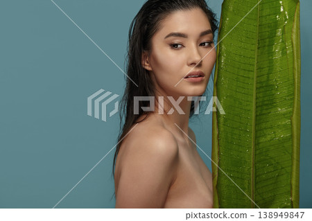 Sensual woman with ideal skin stands near tropical leaf. Sensual woman with ideal skin stands near tropical leaf. 138949847