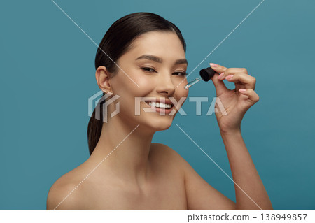 Woman smiling, applying skincare product for face. Woman smiling, applying skincare product for face. 138949857