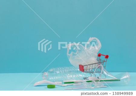 Plastic waste and shopping cart on blue background 138949989