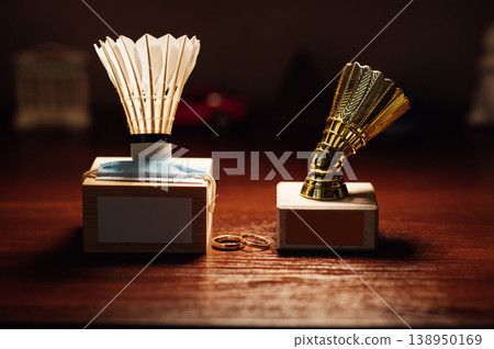 Badminton Pandemic Wedding Concept with Shuttlecock Awards, Mask, and Gold Rings on Wood. Badminton Pandemic Wedding Concept with Shuttlecock Awards, Mask, and Gold Rings on Wood. 138950169