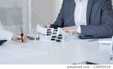 Business people preparing financial documents and signing reports at office desk, analyzing taxation data. Audit and taxes in business Business people preparing financial documents and signing reports at office desk, analyzing taxation data. Audit and taxes in business 138950528