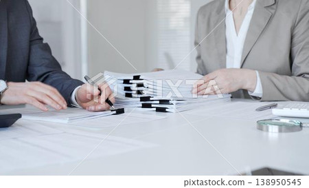Business people reviewing documents in office, collaborating on paperwork and organization task. Audit and taxes in business Business people reviewing documents in office, collaborating on paperwork and organization task. Audit and taxes in business 138950545