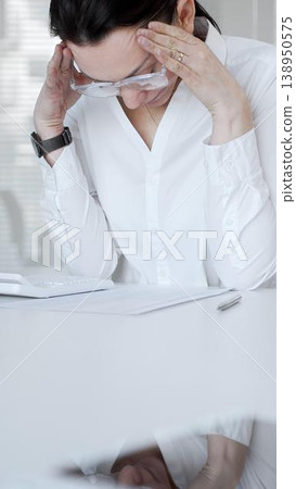 Stressed businesswoman suffering headache and pain, feeling overworked during office hours, facing deadlines and pressure. Audit and taxes in business 138950575