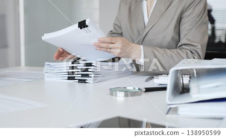Businesswoman hands reviewing financial documents and accounting paperwork for audit, finance, and enterprise records. Audit and taxes concept Businesswoman hands reviewing financial documents and accounting paperwork for audit, finance, and enterprise records. Audit and taxes concept 138950599