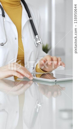 Doctor using tablet, working in clinic office, health care professional analyzing electronic medical records data. Medicine, healthcare and science concept Doctor using tablet, working in clinic office, health care professional analyzing electronic medical records data. Medicine, healthcare and science concept 138950644