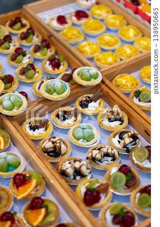 Assorted dessert cups with fruit and chocolate displayed in market stall, colorful sweet selection with orange kiwi grapes and mango, ready for sale in street food setting Assorted dessert cups with fruit and chocolate displayed in market stall, colorful sweet selection with orange kiwi grapes and mango, ready for sale in street food setting 138950665