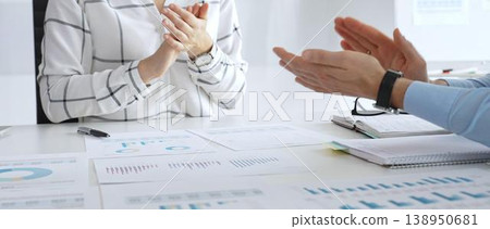 Business people team clapping hands in meeting celebrating success with financial charts, data analysis, sales growth reports, and teamwork achievement in sunny office Business people team clapping hands in meeting celebrating success with financial charts, data analysis, sales growth reports, and teamwork achievement in sunny office 138950681