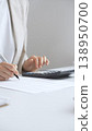 Businesswoman is calculating annual tax using calculator and taking notes in the office, managing domestic budget and checking financial documents. Audit and taxes in business 138950700