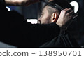 Skilled barber grooming client's hair with precision, working inside contemporary barbershop setting, preparing stylish haircut 138950701