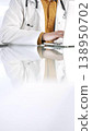 Unknown doctor man in a yellow shirt under a medical coat is using technology in medicine. Close-up of hands typing on a laptop on a glass desk in the clinic, vertical view. Health care concept 138950702