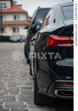 Black car parked on cobblestone street near buildings in city setting Black car parked on cobblestone street near buildings in city setting 138950818
