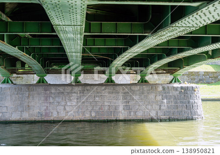 Underneath the bridge, the metal structure connects over the calm water below on a sunny day Underneath the bridge, the metal structure connects over the calm water below on a sunny day 138950821
