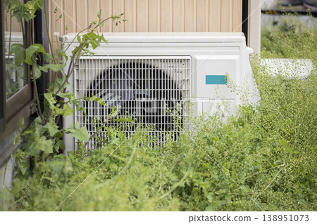Air conditioner outdoor unit covered in weeds Air conditioner outdoor unit covered in weeds 138951073