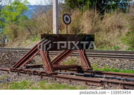 Railway buffer stop at end of track, metal barrier safety device, transport infrastructure detail, countryside rail line, industrial, travel concept 138953454