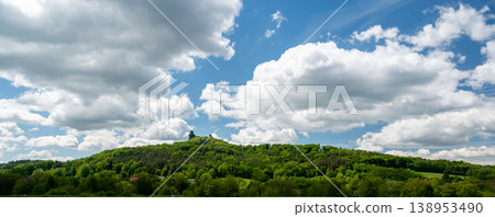 Panoramic view of Cesky Raj landscape in summer with iconic Trosky castle towers rising above green countryside under blue sky with dramatic clouds summer scenic natureview stock 138953490