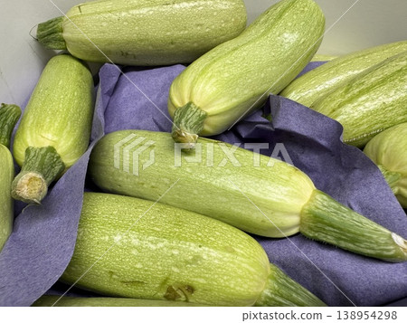 Green zucchinis arranged on purple fabric create a vibrant background for fresh produce concepts Green zucchinis arranged on purple fabric create a vibrant background for fresh produce concepts 138954298