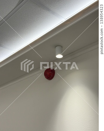 Ceiling with smoke detector and cylindrical light fixture in office setting Ceiling with smoke detector and cylindrical light fixture in office setting 138954323