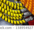 Hoses with yellow and black stripes connect to machinery in an industrial setting during daylight hours 138954927