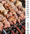 Grilling meat on skewers in an outdoor setting during a sunny day in a backyard barbecue 138954930