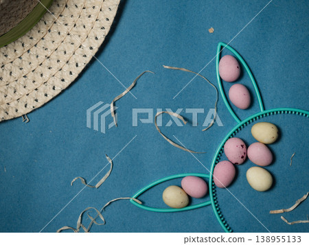 Easter display with bunny rabbit ears eggs and bonnet on blue background Easter display with bunny rabbit ears eggs and bonnet on blue background 138955133