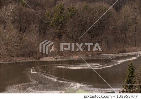 Winding River with Ice Floats Amidst Deciduous Forest in Late Autumn or Early Winter 138955477