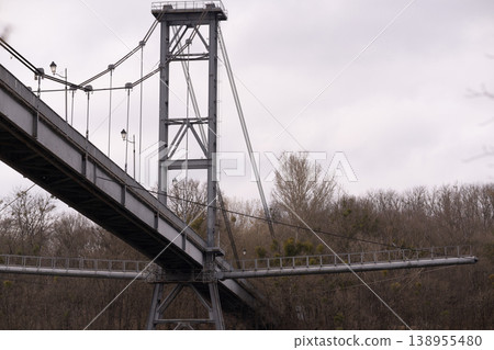 Low Angle View of Metal Suspension Bridge Structure Against Overcast Sky Low Angle View of Metal Suspension Bridge Structure Against Overcast Sky 138955480