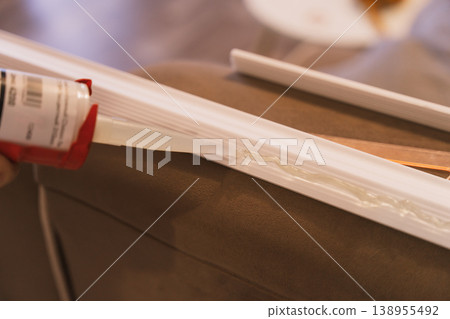 Close up applying construction adhesive to molding strip, DIY home improvement concept 138955492