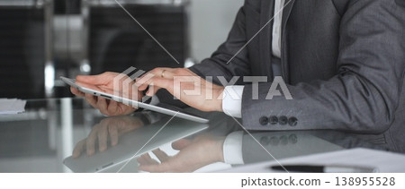Businessman in a modern office using a digital tablet, managing data and corporate tasks, embracing mobile technology for productivity and efficient communication during a meeting, close up. Businessman in a modern office using a digital tablet, managing data and corporate tasks, embracing mobile technology for productivity and efficient communication during a meeting, close up. 138955528