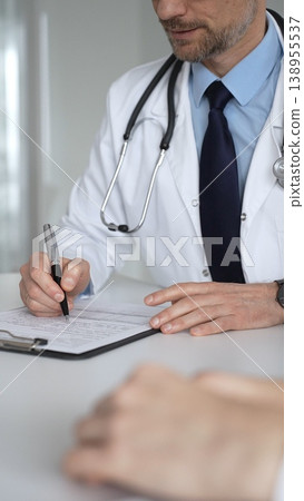 Doctor in white coat explaining test results to a patient using a digital tablet during a medical appointment. Medicine, healthcare and science concept Doctor in white coat explaining test results to a patient using a digital tablet during a medical appointment. Medicine, healthcare and science concept 138955537