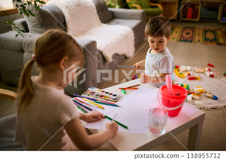 Little children drawing together at table using pencils and watercolor paints at home. 138955712
