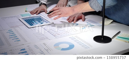 Analyzing financial data and business reports on a tablet and paper charts, collaborating on a project strategy, examining market trends for successful startup growth Analyzing financial data and business reports on a tablet and paper charts, collaborating on a project strategy, examining market trends for successful startup growth 138955737