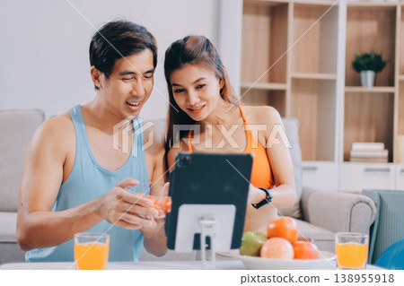 A happy couple prepares fresh vegetables, laughing and enjoying cooking a healthy meal together. A happy couple prepares fresh vegetables, laughing and enjoying cooking a healthy meal together. 138955918
