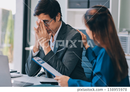 Millennial Asian stressed depressed worried thoughtful professional male businessman female businesswoman employee staff in formal business suit sitting thinking solving problem ideas in office room 138955978
