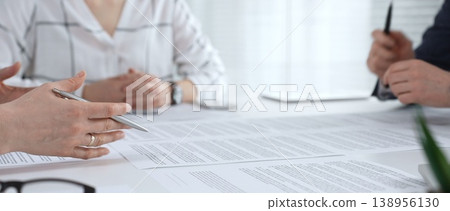 Business people collaborating at a conference table, reviewing paperwork, sharing ideas, and reaching a mutual agreement during a professional meeting or consultation Business people collaborating at a conference table, reviewing paperwork, sharing ideas, and reaching a mutual agreement during a professional meeting or consultation 138956130