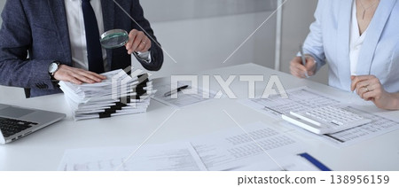 Professional accountant team analyzing corporate financial data, managing paperwork, and preparing tax reports, collaborating on bookkeeping and auditing tasks at a desk. Audit and taxes Professional accountant team analyzing corporate financial data, managing paperwork, and preparing tax reports, collaborating on bookkeeping and auditing tasks at a desk. Audit and taxes 138956159