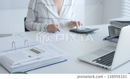 Calculator on financial documents, with an accountant taking notes, emphasizing accounting, finance, and tax preparation, close up. Audit and taxes in business 138956181