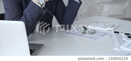 Stressed businessman struggling with financial problems, feeling overwhelmed by paperwork, debt, and the pressure of work, experiencing burnout and failure. Audit and taxes 138956229