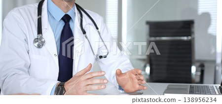 Male doctor communicating with patient at a clinic desk, offering professional healthcare guidance and explaining a diagnosis. Medicine, healthcare and science concept Male doctor communicating with patient at a clinic desk, offering professional healthcare guidance and explaining a diagnosis. Medicine, healthcare and science concept 138956234