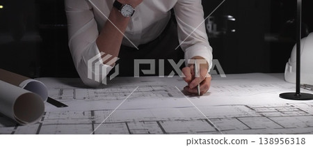 Architect carefully planning building blueprint, thinking about engineering design and development at late night workstation. Business and architect people concept Architect carefully planning building blueprint, thinking about engineering design and development at late night workstation. Business and architect people concept 138956318