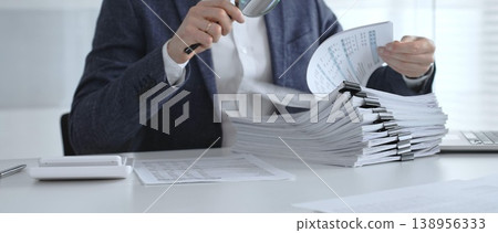 Professional reviewing corporate financial statements with magnifying glass, auditing reports, taxes and expense details. Audit and taxes Professional reviewing corporate financial statements with magnifying glass, auditing reports, taxes and expense details. Audit and taxes 138956333