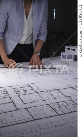 Female architect drawing blueprints for a residential building project, creating innovative urban design plans. Architecture and business concept in low key lighting Female architect drawing blueprints for a residential building project, creating innovative urban design plans. Architecture and business concept in low key lighting 138956411
