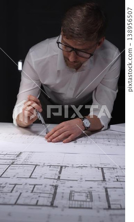 Architect creating technical drawing with compass, designing blueprint on paper for engineering project in office. Concept of architecture and business in low key lighting Architect creating technical drawing with compass, designing blueprint on paper for engineering project in office. Concept of architecture and business in low key lighting 138956507