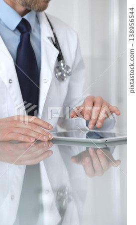 Doctor using digital tablet, consulting with patient, working in healthcare office, telemedicine and medical technology concept. Medicine and health care Doctor using digital tablet, consulting with patient, working in healthcare office, telemedicine and medical technology concept. Medicine and health care 138956544