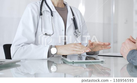 Doctor consulting patient, discussing diagnosis, using digital tablet in modern medical clinic. Medicine and health care Doctor consulting patient, discussing diagnosis, using digital tablet in modern medical clinic. Medicine and health care 138956593