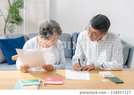 Senior couple filling out paperwork for end-of-life planning. Senior couple filling out paperwork for end-of-life planning. 138957127