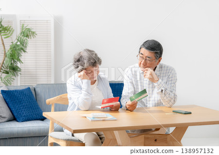 A senior couple reflects while looking at their bankbook. A senior couple reflects while looking at their bankbook. 138957132