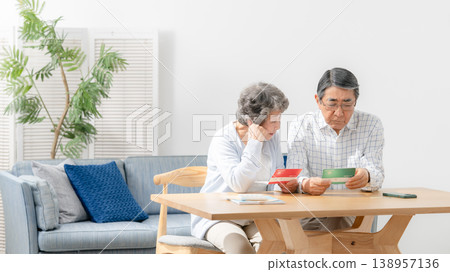A senior couple reflects while looking at their bankbook. A senior couple reflects while looking at their bankbook. 138957136
