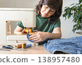 An adult woman repairs and alters denim jeans on a sewing machine at home, focused on an upcycling diy craft project. Reusing things. Environmental awareness. Eco-friendly lifestyle 138957480